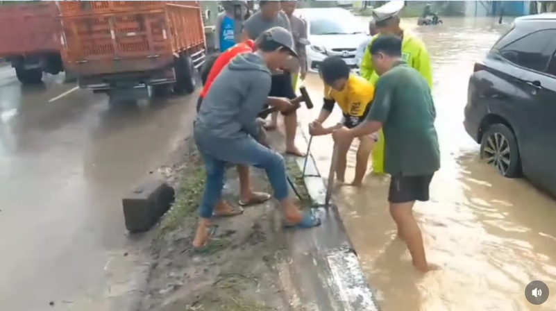 Pembongkaran median jalan akibat luapan air Kali Babon (foto: Polsek Genuk)